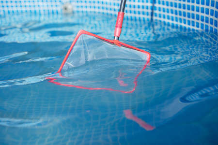 Cleaning the surface of your home pool with a netの写真素材