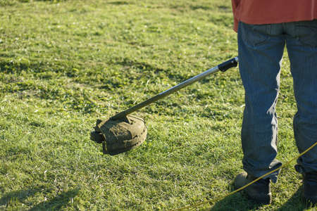 A man mows the grass on the front lawn with a mower