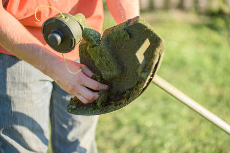 A man mows the grass on the front lawn with a mower