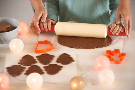 Mom and daughter roll out the dough for gingerbread cookies using a rolling pin. Preparing for the...