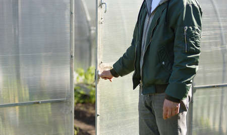 The man opens the door to the greenhouse. Beginning of the agricultural season, gardening