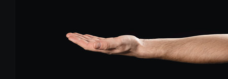 man holding out his hand with a something. Isolated on blackの写真素材