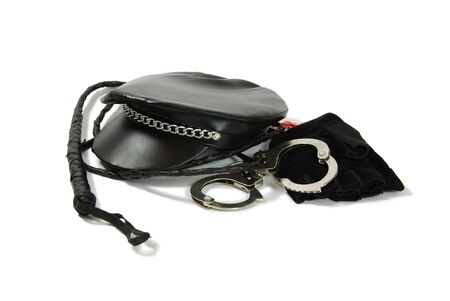 Whip made of woven leather, Leather biker cap with a chain across the bill, Handcuffs made of metal with mechanical clasp, black leather glovesの写真素材
