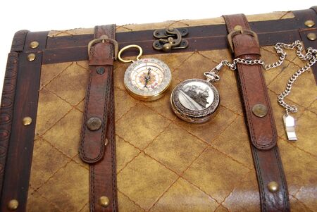Silver train pocket watch and brass compass on a leather and wood traveling trunkの写真素材