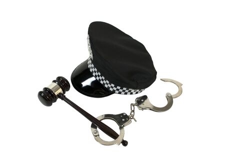 Symbols of authority shown by a black police hat with a set of handcuffs and a wooden gavelの写真素材