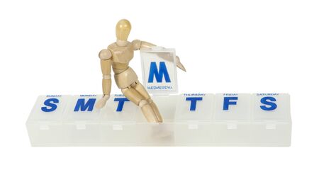 Daily medical caretaker shown by a model sitting in a daily pill minder container for dividing up prescription medication into daily doses - path includedの写真素材