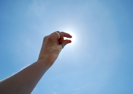A pinch of sunshine shown by a hand up in the sky in a pinching motion