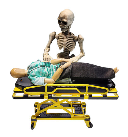 A standing Skeleton holding his hands out on a gurney where a patient lies