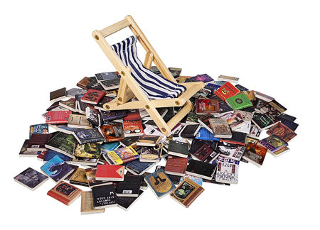 Folding beach chair for easy seating at the beach on a pile of booksの写真素材