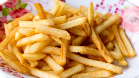 French Fries closeup on the colorful dish isolated on white background