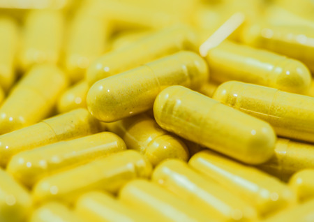 Piles of yellow capsules background macro