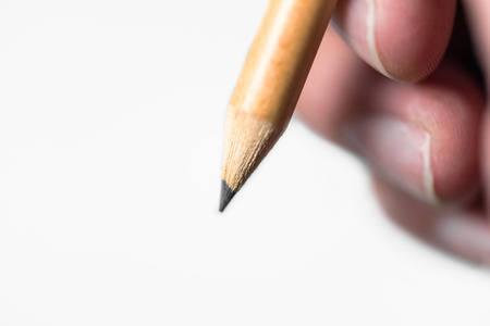 Wooden Pencil is hold by human to write something on hand isolated on white backgroundの写真素材