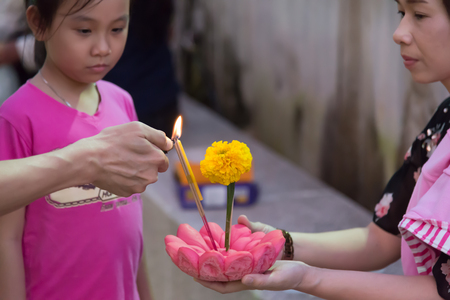 Nakhon Si Thammarat, Thailand - November 6,2014 : Unidentified girl  with mother  holds Krathong ,floating flora basket, for ignite candle on Loi Krathong traditional day, one of the most  famous  festival in Thailandのeditorial素材