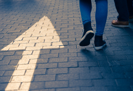 White arrow straight sign on street with walking peopleの写真素材