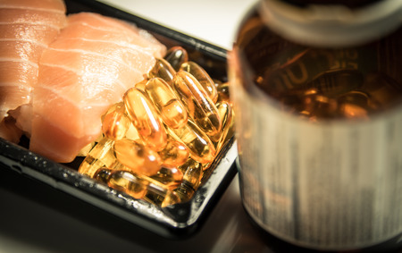 Sushi served with piles of fish oil capsules food supplement near brown bottle golden vintage toneの写真素材