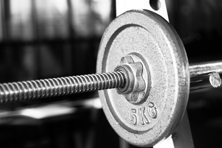 Barbell focused on 5 kg plate closeup black and whiteの写真素材
