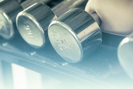 Asian male  hand grab dumbell  focused on 5 kg one with soft light