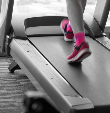 Unknown woman with pink shoes running in treadmill in the gym for workout split tone pink black and...