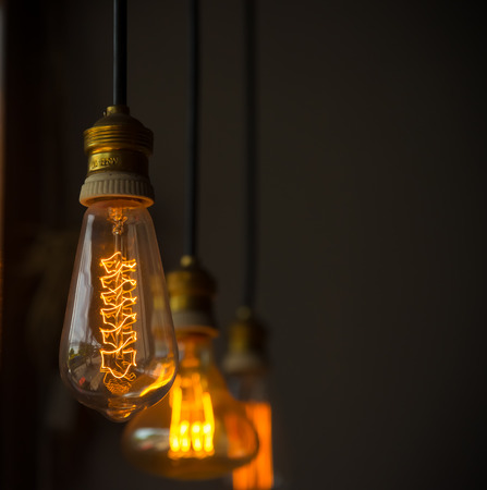 Hanged  decoration light bulbs focus on middle one  in dark room vintage tone vertical