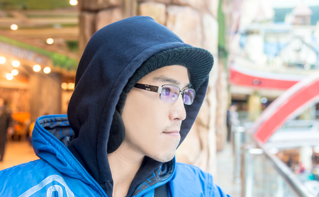 Asian male in hood wear sunglasses looking forward  alone in city indoorの写真素材