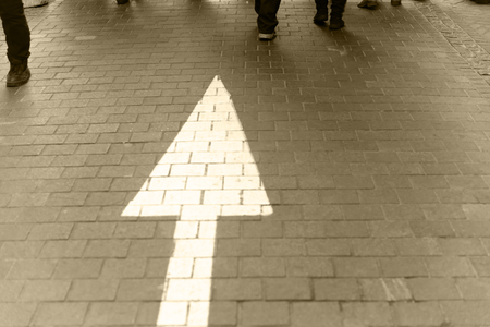 White arrow straight on pavement walking street with walking people vintage sepia toneの写真素材