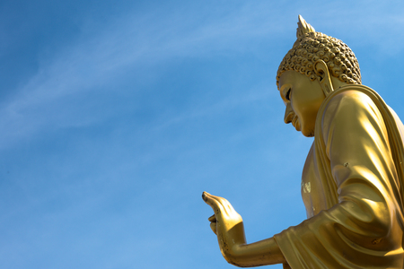 Golden buddha hand on 'O.K.' sign (peace) with blue sky and clouds with smileの写真素材