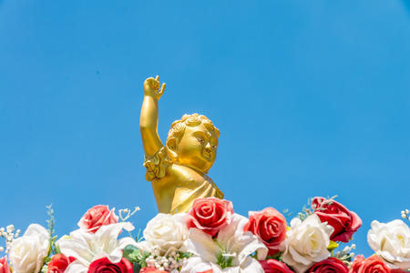 Golden baby Buddha statue raise arm and point forefinger up to blue sky poseの写真素材