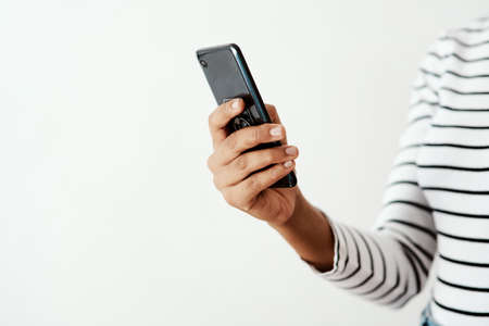 Friends are never far away with your smartphone. Cropped shot of a woman using a smartphone against...