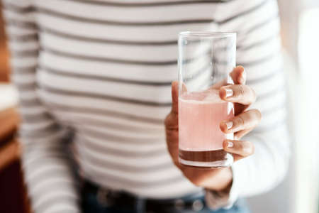 Get a good dose of health in a glass. Cropped shot of a woman having an effervescent drink at home.の写真素材
