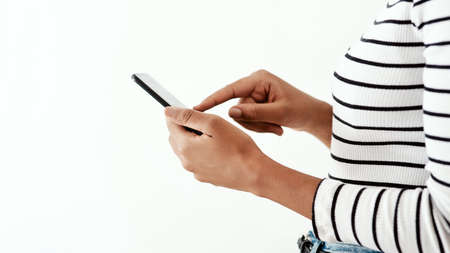 The whole world at the touch of an icon. Cropped shot of a woman using a smartphone against a white...