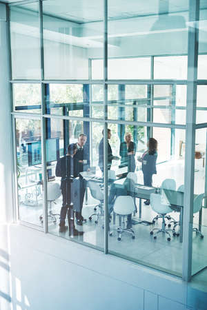 Catching up after the meeting. High angle shot of a group of corporate businesspeople meeting in the boardroom.の写真素材