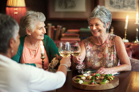 Lets drink to a lifetime of happiness. Cropped shot of a group of senior female friends enjoying a lunch date.の写真素材