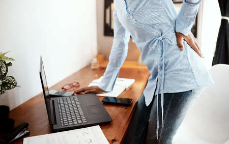 Time to get a new office chair. Cropped shot of a businesswoman experiencing back pain at work.の写真素材
