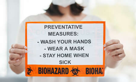 Heres how to protect yourself. Shot of a woman holding up a sign with a list of COVID-19 prevention measures.の写真素材