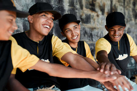If we win, we win as a team. Cropped shot of a group of young baseball players sitting together on the bench during a game.の写真素材