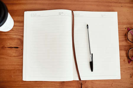 Plan your way to a productive day. Shot of a notebook and pen on a desk in an office.の写真素材