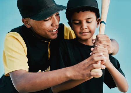 Im training him to be a great player. Shot of a young baseball player showing a little boy how to play.の写真素材