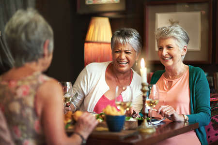Wining, dining and reminiscing. Cropped shot of a group of senior female friends enjoying a lunch date.の写真素材