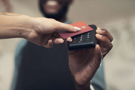 Paying just got easier in our store. Shot of an unrecognizable man standing in his bicycle shop and assisting a customer with her purchase.の写真素材