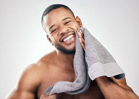 Fresh-faced and ready for the day. Studio portrait of a handsome young man wiping his face with a towel against a white background.の写真素材