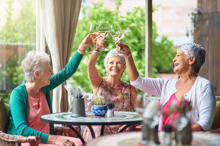 Cheers to a fun retirement with you girls. Cropped shot of a group of senior female friends enjoying a lunch date.の写真素材
