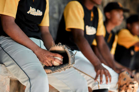Were ready to play. Cropped shot of a group of young baseball players sitting together on the bench during a game.の写真素材