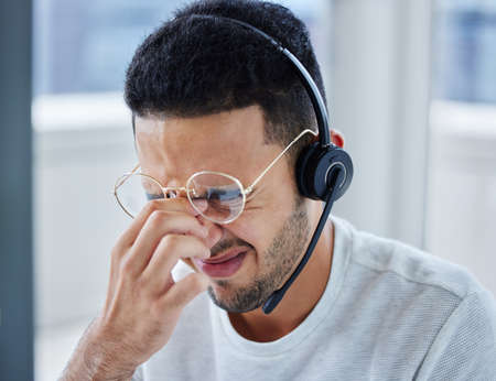 This client has me stressed out. Shot of a young businessman suffering s headache at his desk in his office.の写真素材