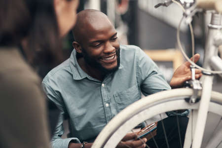 This is exactly what Ive been looking for. Shot of a handsome young man crouching down and looking at a bicycle before buying it.の写真素材