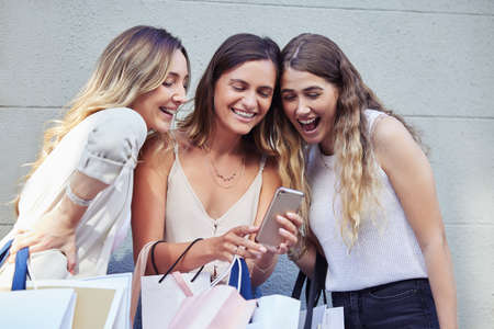 He just sent me a text. Shot of a group of female friends hanging out outside while using a...