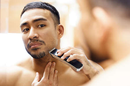 My date wont even recognise me tonight. Shot of a young man using an electric shaver.の写真素材