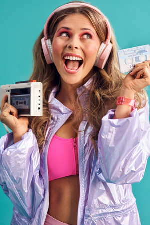 I have the greatest 80s hits on here. Studio shot of a young woman holding a cassette player while...
