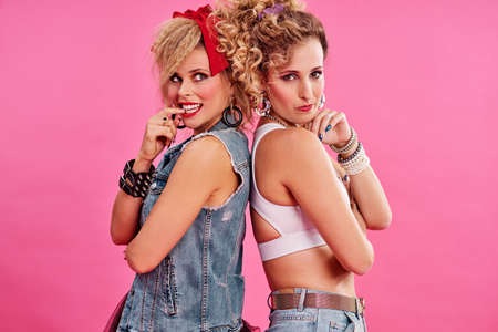 Bad girls have all the fun. Studio shot of two beautiful young women styled in 80s clothing.の写真素材
