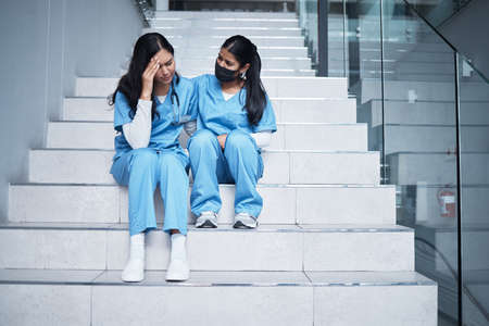 We did our best back there. Shot of a female nurse comforting her colleague while sitting on a staircase at work.の写真素材