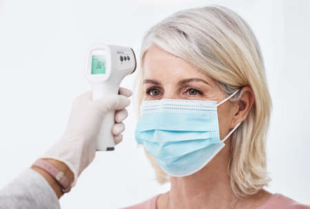 A normal temperature gets you through the door. Shot of a woman wearing a mask while having a...